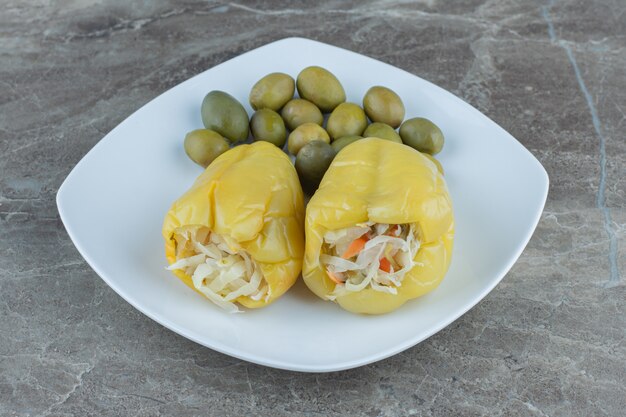 Peperoni in scatola ripieni di crauti con oliva sul piatto bianco.