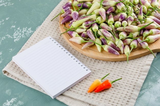 Peperoni sul tagliere con la vista dell'angolo alto del taccuino sull'asciugamano di cucina e del gesso