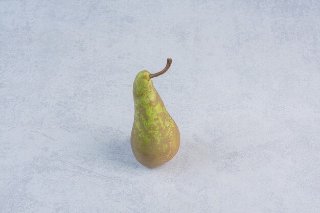 Pera verde succosa organica su fondo grigio.