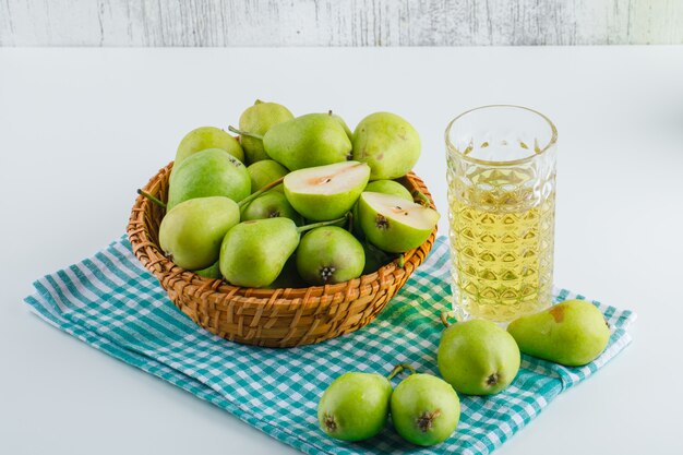 Pere in un cestino con la bevanda, vista dell'angolo alto dell'asciugamano di cucina sulla tabella bianca