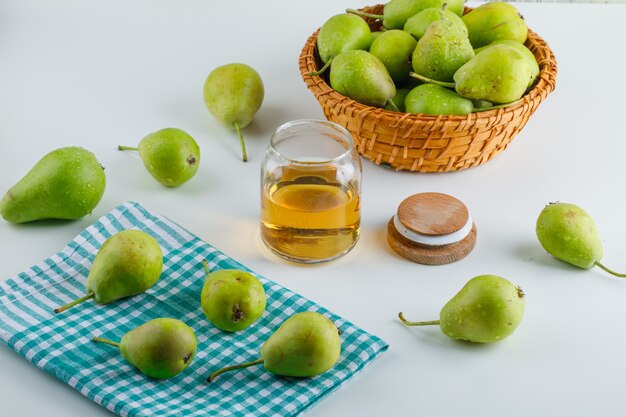 Pere in un cestino con la vista dell'angolo alto del miele su bianco e sul tovagliolo di cucina