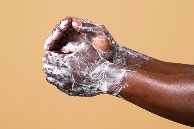 Persona africana che si lava le mani con il sapone isolato sull'arancia