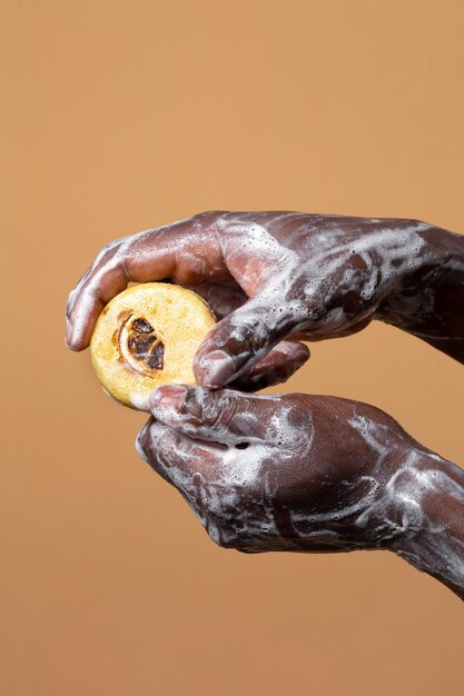 Persona africana che si lava le mani con il sapone isolato sull'arancia