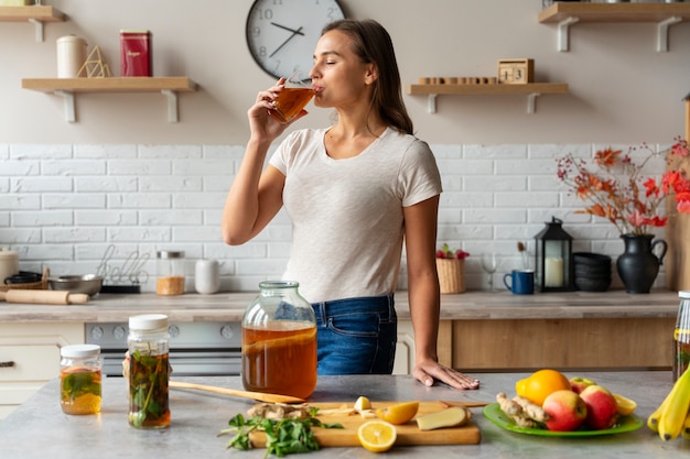 Persona che beve kombucha a casa in cucina