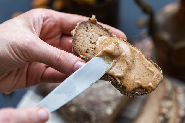 Persona che mette la crema di mandorle su un pane vegano con un coltello
