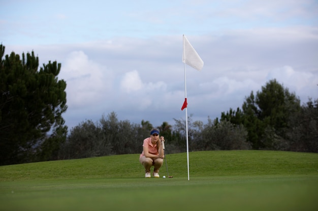 Persona che mira alla bandiera del golf