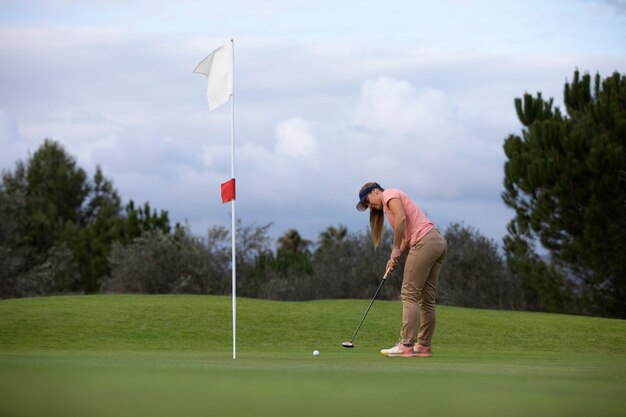 Persona che mira alla bandiera del golf