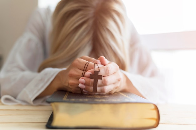 Persona che prega mentre tiene croce e libro sacro