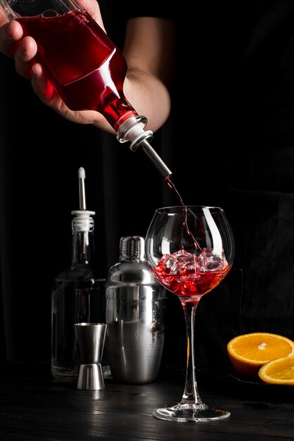 Persona che prepara cocktail con alcol e arancia