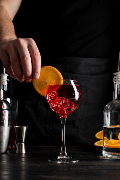 Persona che prepara cocktail con alcol e arancia