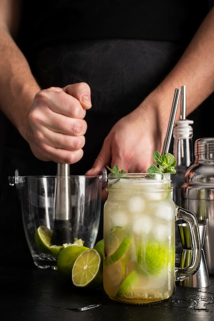 Persona che prepara cocktail con alcol e lime