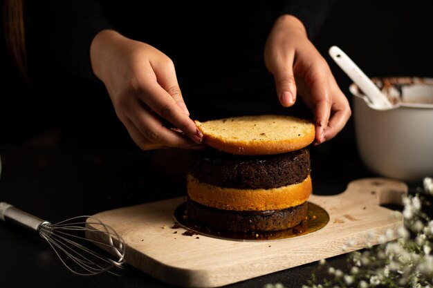 Persona che prepara una piccola torta con strati di cioccolato e vaniglia