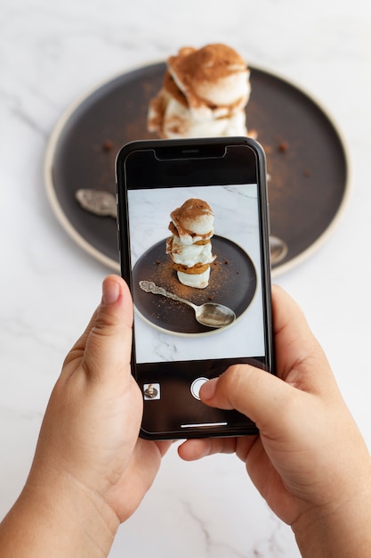 Persona che scatta foto con lo smartphone del dessert con cacao in polvere