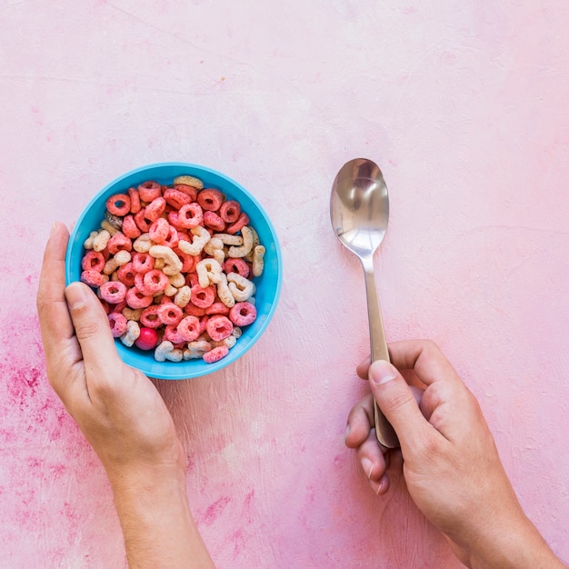 Persona che tiene cucchiaio e ciotola con cereali