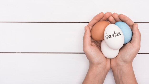 Persona che tiene le uova colorate con iscrizione di Pasqua