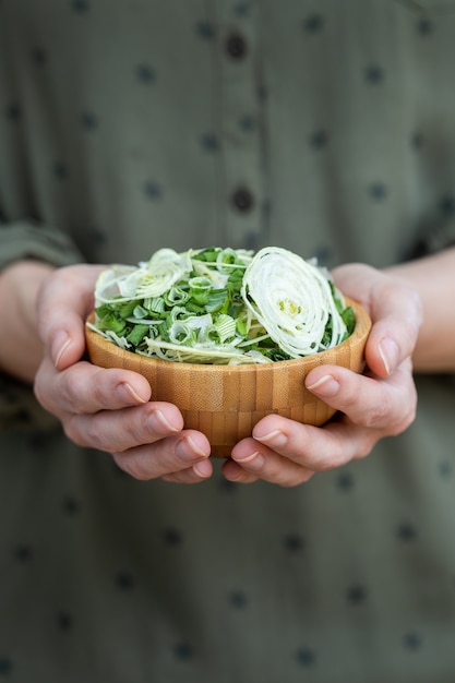 Persona che tiene una ciotola di insalata fatta di cipolle disidratate