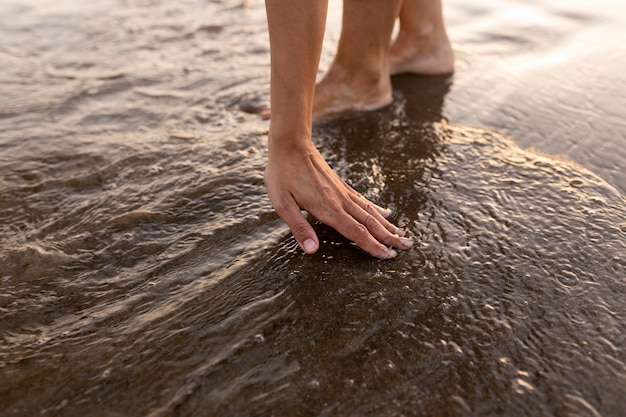 Persona che tocca l'acqua in spiaggia