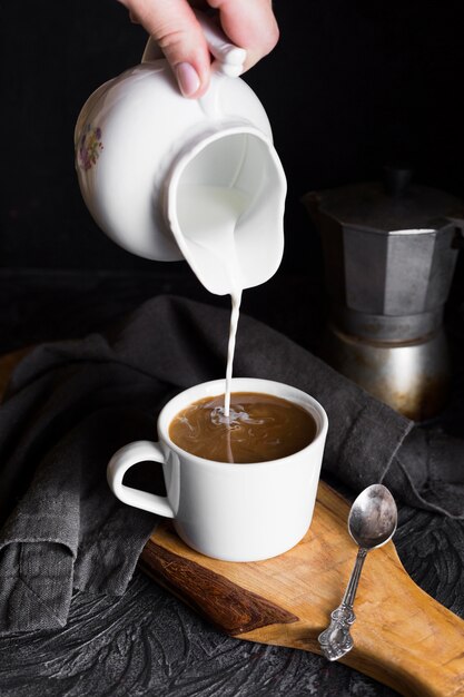 Persona che versa mil in tazza di caffè