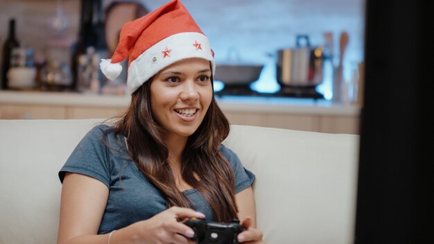 Persona con cappello da Babbo Natale vincendo videogiochi con joystick