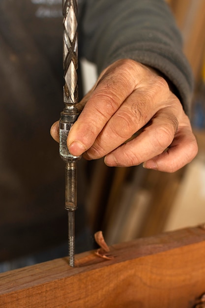 Persona del primo piano che perfora un buco nel legno