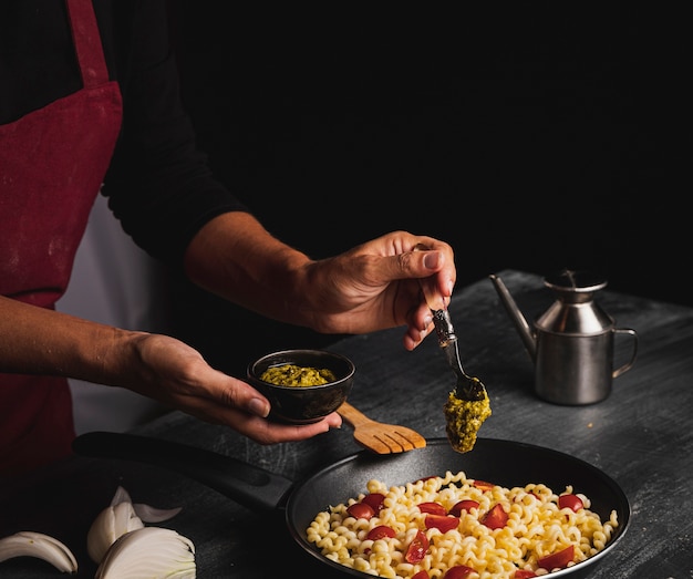 Persona del primo piano che prepara pasta in pentola