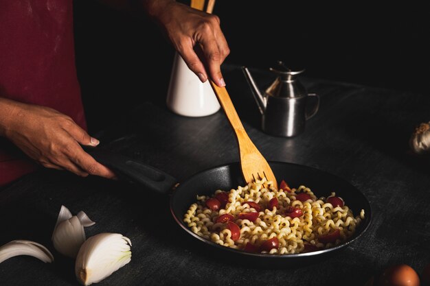 Persona del primo piano che produce pasta in pentola