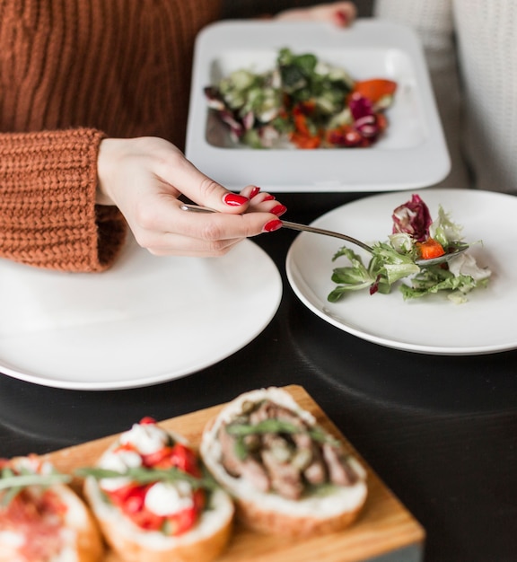 Persona del primo piano che serve insalata deliziosa