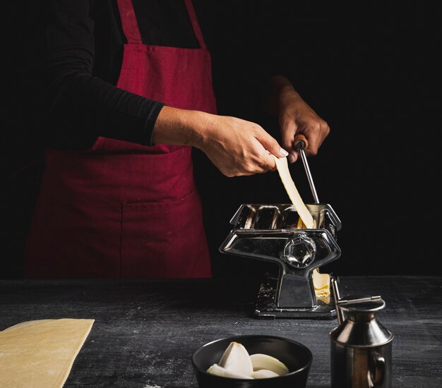 Persona del primo piano con il grembiule rosso e la macchina della pasticceria