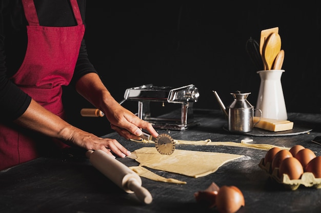 Persona del primo piano con la taglierina e la pasta della pizza