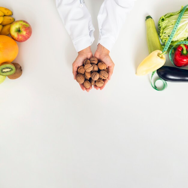 Persona del primo piano con le verdure che tengono le noci