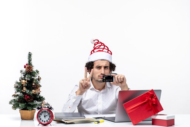 Persona di affari con il cappello di Babbo Natale e tenendo la sua carta di credito guardando con sorpresa in ufficio