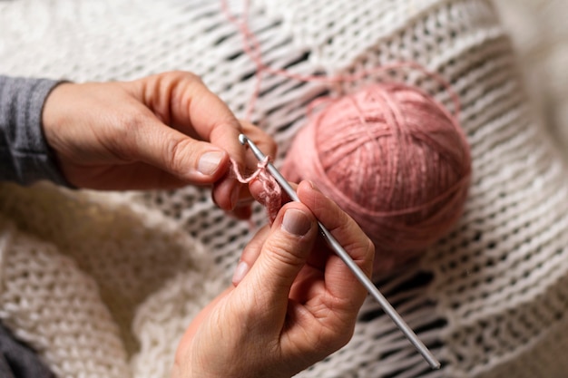 Persona di alta vista che lavora a maglia con filo rosa