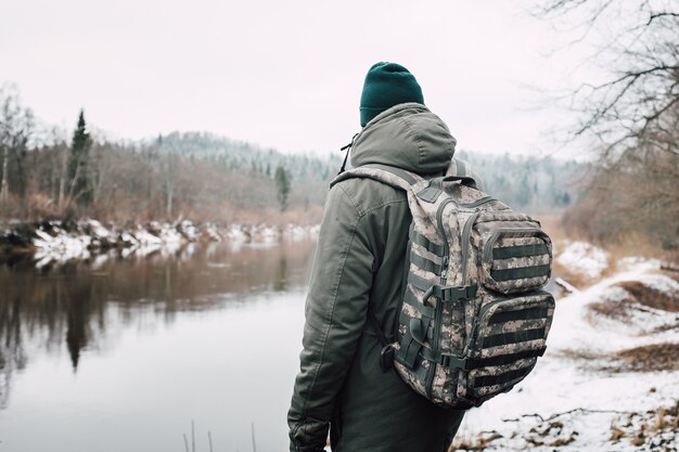 Persona di fronte al lago circondata da alberi durante l'inverno