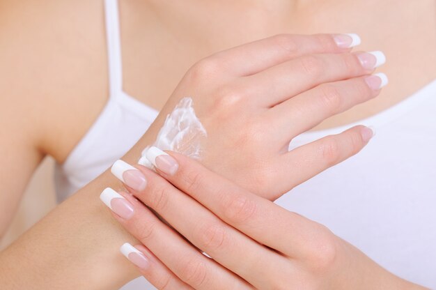 Persona di sesso femminile irriconoscibile che applica crema idratante cosmetica a portata di mano