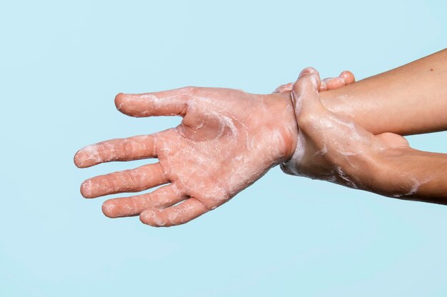 Persona di vista laterale che lava le mani isolate sull'azzurro
