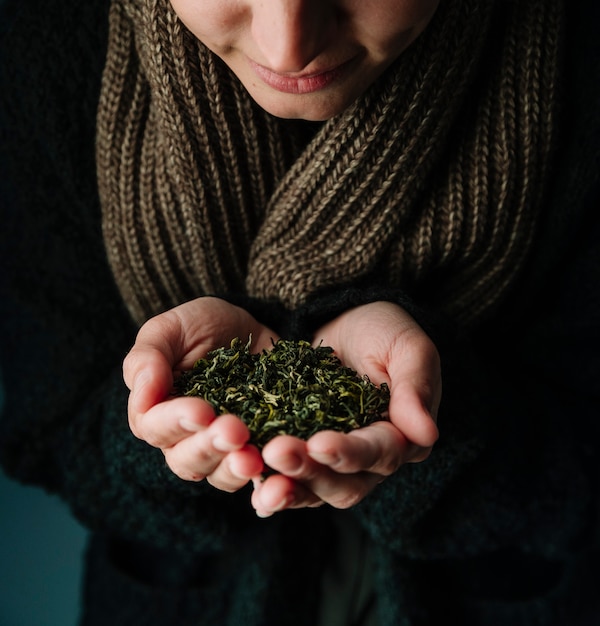 Persona in possesso di erbe del tè e indossa una sciarpa