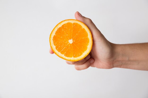 Persona in possesso di metà di frutta arancione