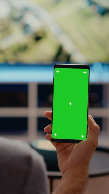 Persona in possesso di telefono cellulare con schermo verde in verticale