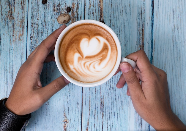 persona in possesso di una tazza di caffè latteo