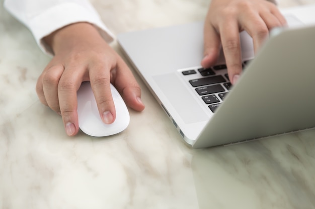 Persona scrittura con una mano e l&#39;altra tocca un mouse