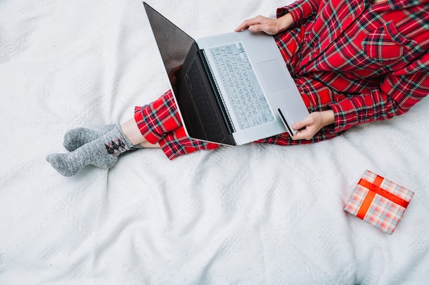 Persona seduta sul letto con il portatile