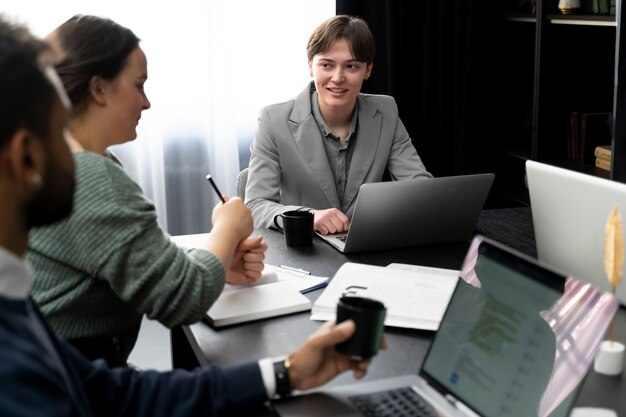 Persona trans che lavora in ufficio con i colleghi