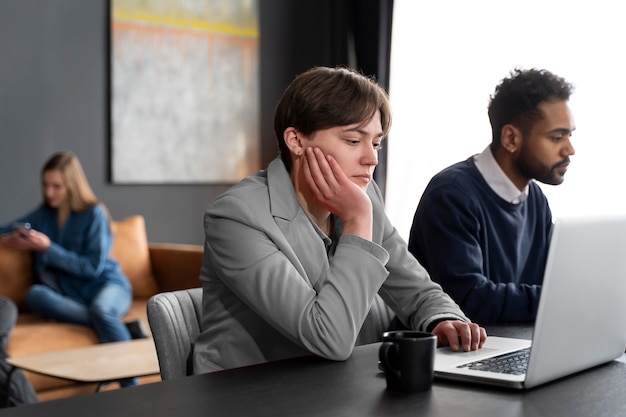 Persona trans che lavora in ufficio con i colleghi