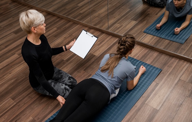 Personal trainer femminile che aiuta la sua vista alta del cliente