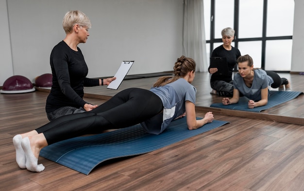 Personal trainer femminile e il suo cliente che fanno la plancia