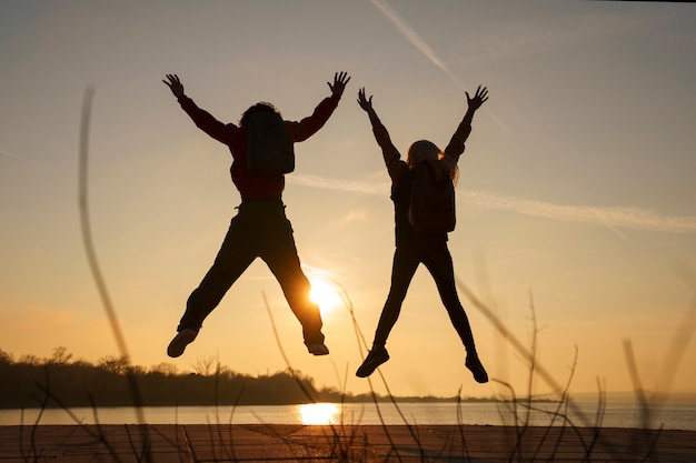 Persone a tutto campo che saltano al tramonto