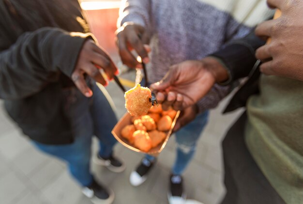 Persone ad alto angolo che mangiano pepite di pollo dalla confezione da asporto