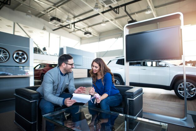 Persone alla concessionaria di veicoli che acquistano auto nuove