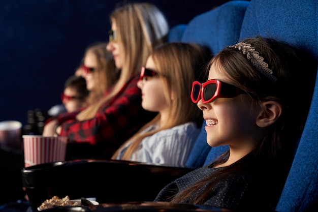 Persone, bambini che guardano film in occhiali 3d al cinema.