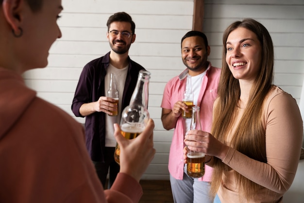 Persone che applaudono e bevono birra mentre giocano a beer pong a una festa al coperto